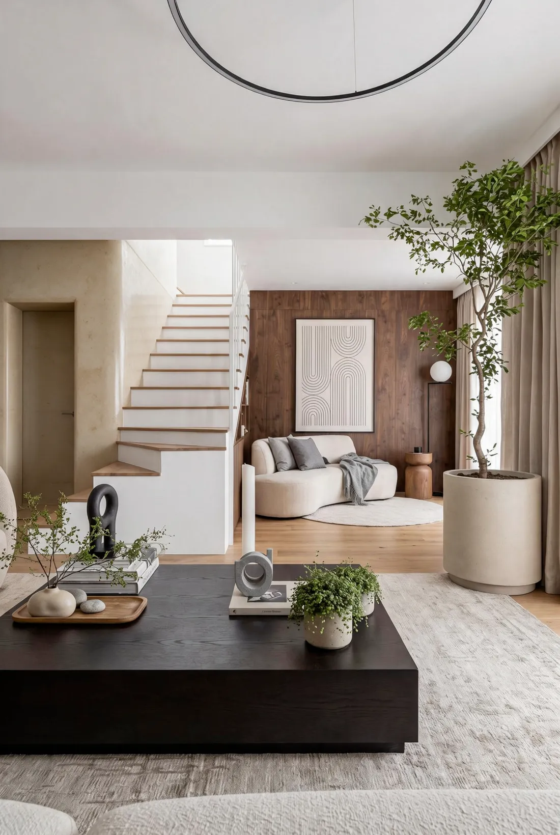 Living con mesa ratona de madera oscura, escalera con peldaños de roble y pared revestida en nogal, proyecto La Pampa