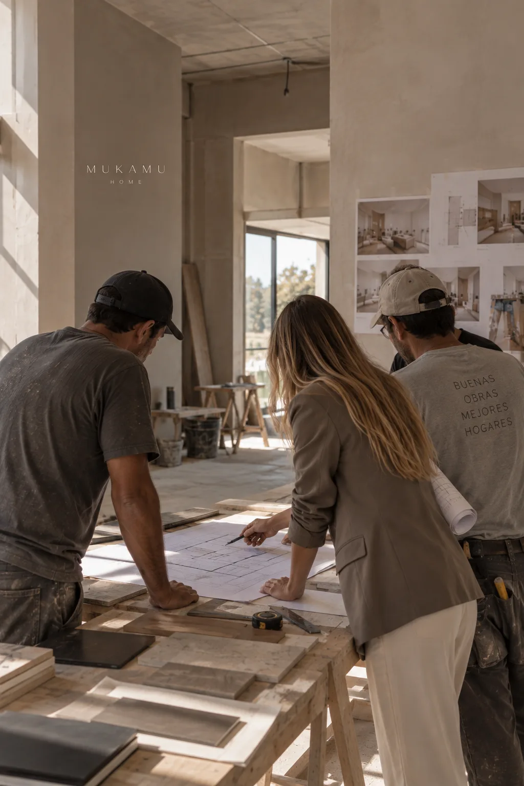 Equipo de MÚKAMÜ HOME revisando planos junto a los responsables de obra, sobre una mesa con muestras de materiales y láminas del proyecto